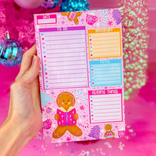 A notepad with sections for a to do list, important items, notes, and reading things. Featuring a gingerbread reading a book in the lower left corner and snowflakes along the top.