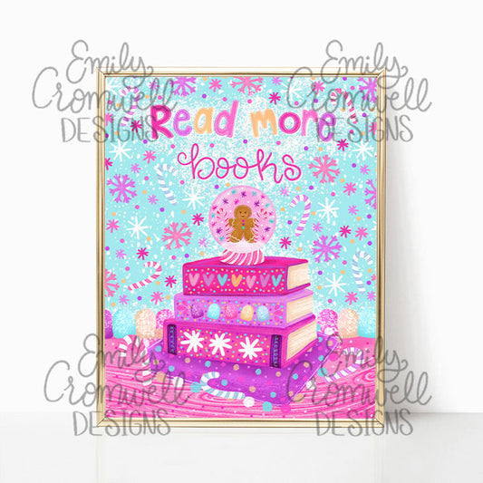 A framed art print against a white background. The print features an illustration of a gingerbread in a snow globe on top of a stack of four purple and pink books, a blue background with candy canes and stars everywhere, and the words "read more books"