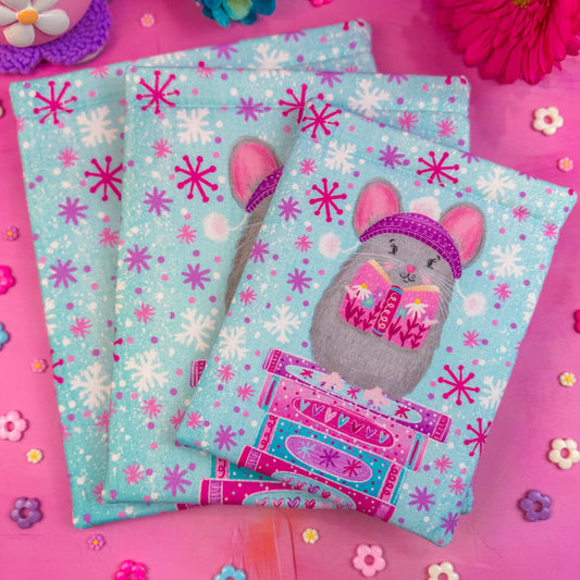 A stack of three Winter Mouse book sleeves on a pink background.